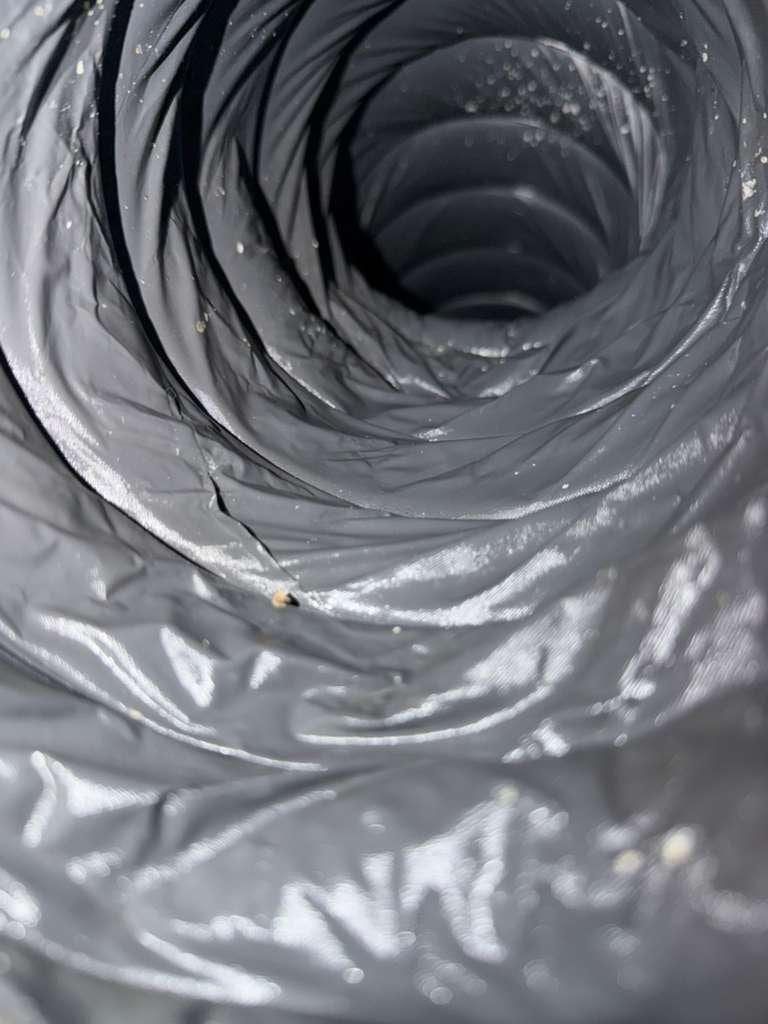 The same kind of spiral metal duct after cleaning, the lining visibly clear of the dust seen before