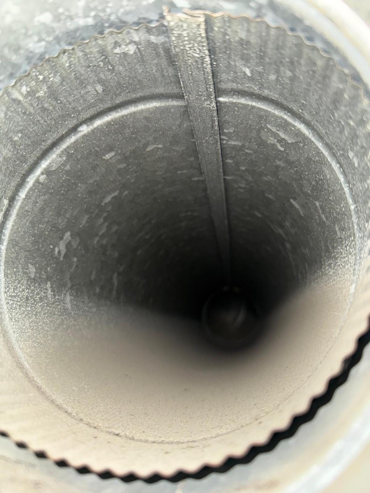 The inside of a rigid metal duct at a round collar, with a foil-tape seam running across the joint