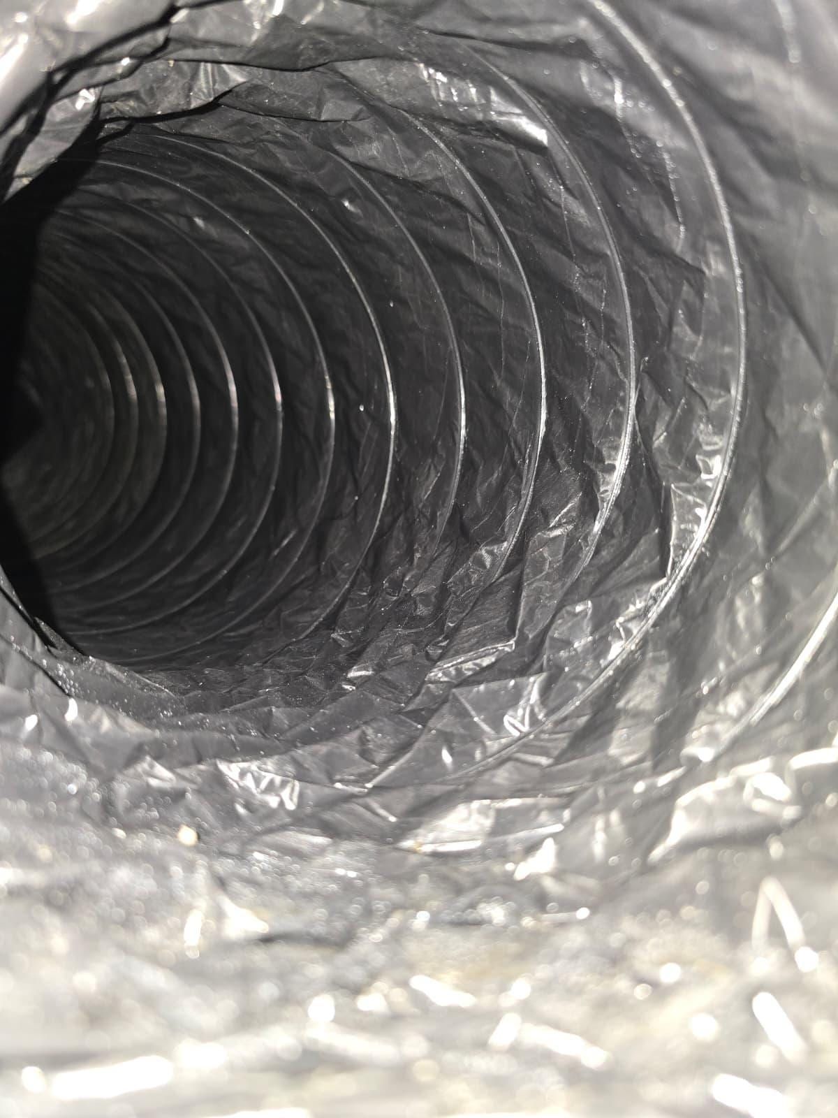 The inside of a flexible duct: a glossy black sleeve spiralling away from the camera over its wire helix