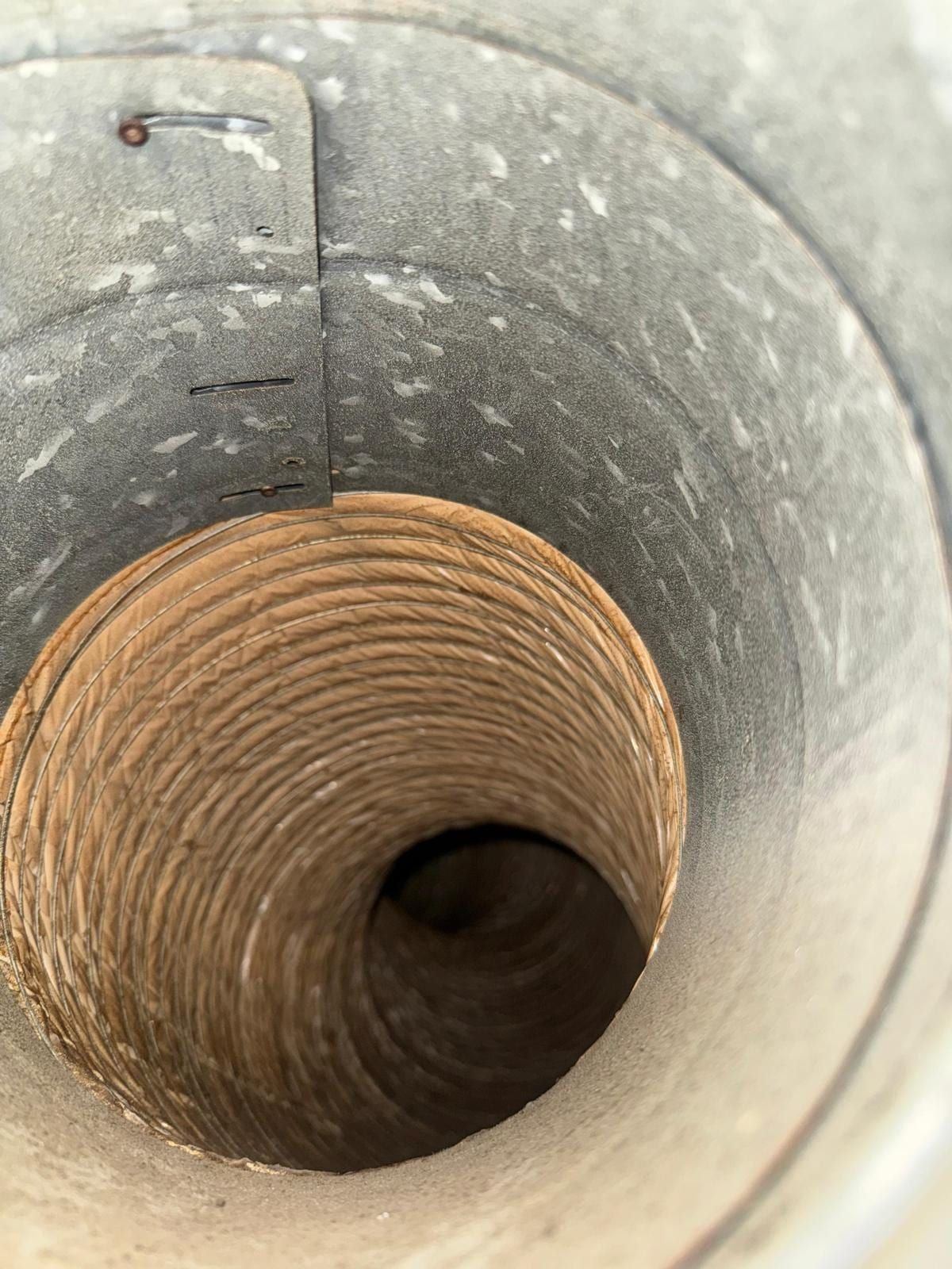 The inside of a galvanised duct trunk with a flexible duct collar joint, lightly dusted