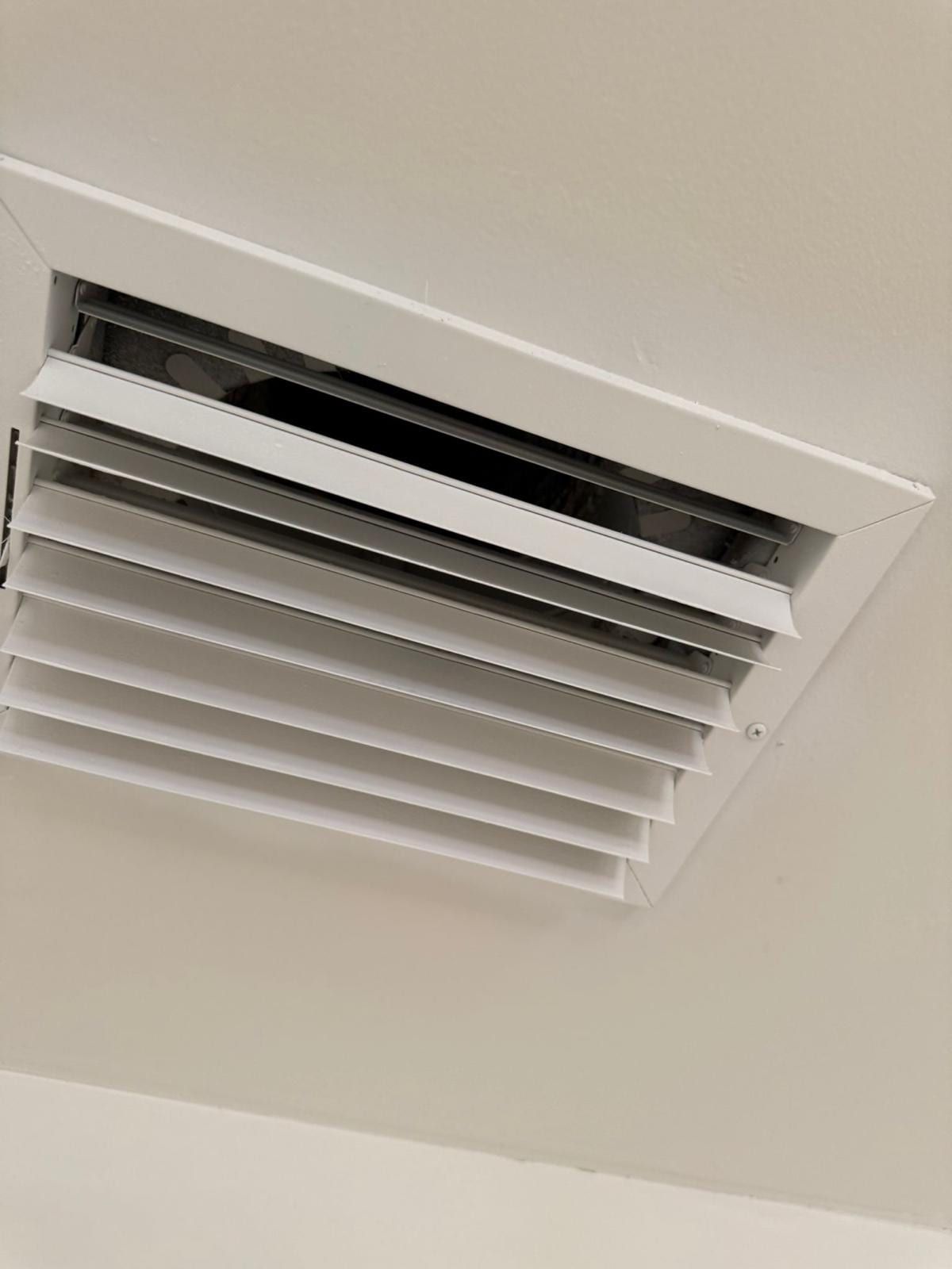 Clean white ceiling supply register, its louvers open and free of dust