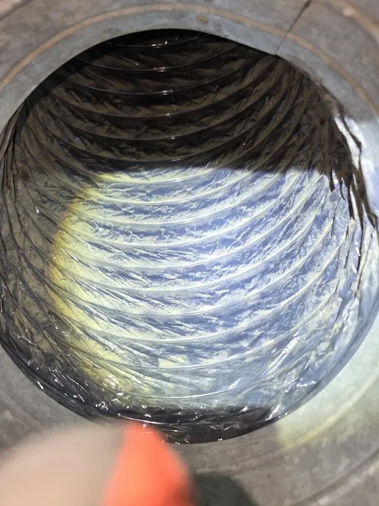 Interior view of a residential ductwork showing buildup of dust and debris on duct walls.