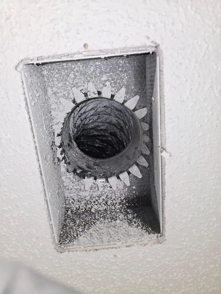 Dusty dryer vent duct showing clogged lint buildup inside wall cavity.