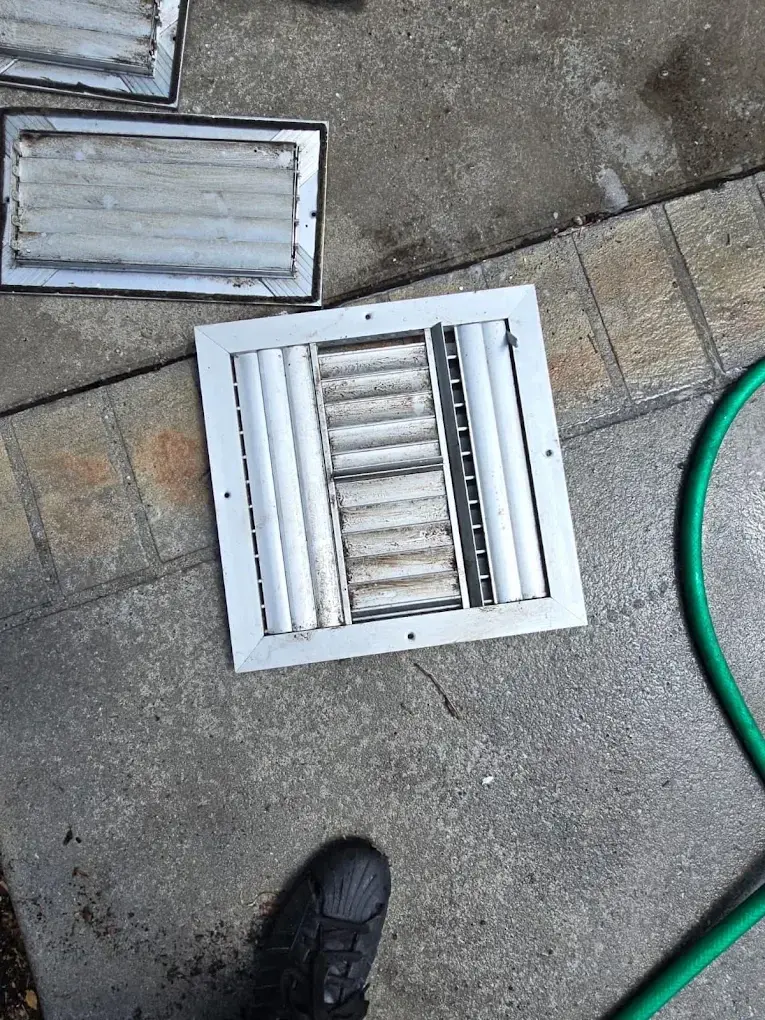 HVAC technician inspecting air return vents and ductwork during maintenance service.