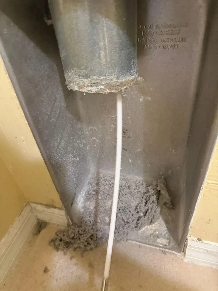 Dryer vent duct showing lint accumulation and blockage requiring cleaning.